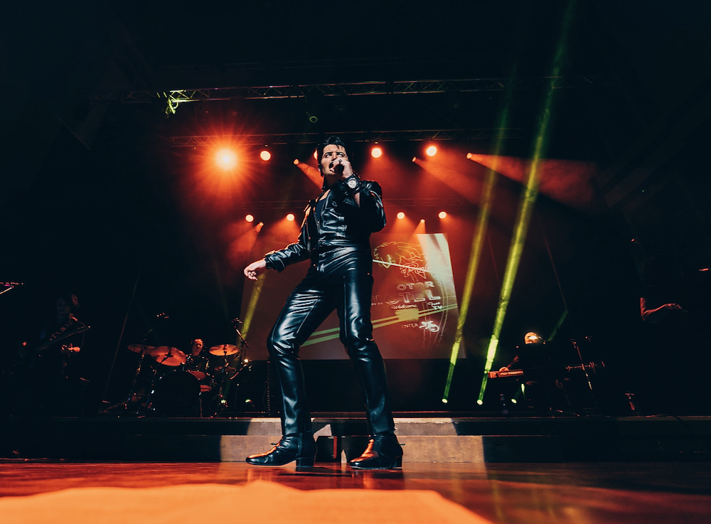A Vision of Elvis tribute performer in 68 Comeback black leather performing live on stage under concert lights