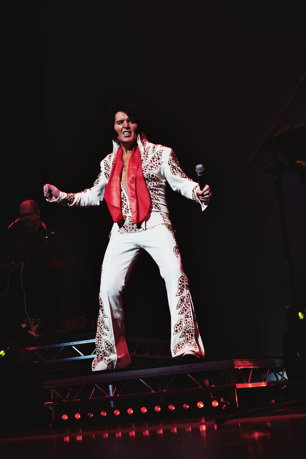 Rob Kingsley performing A Vision of Elvis live on stage in the Stone & Flame Elvis suit with red scarf and microphone 👑📸