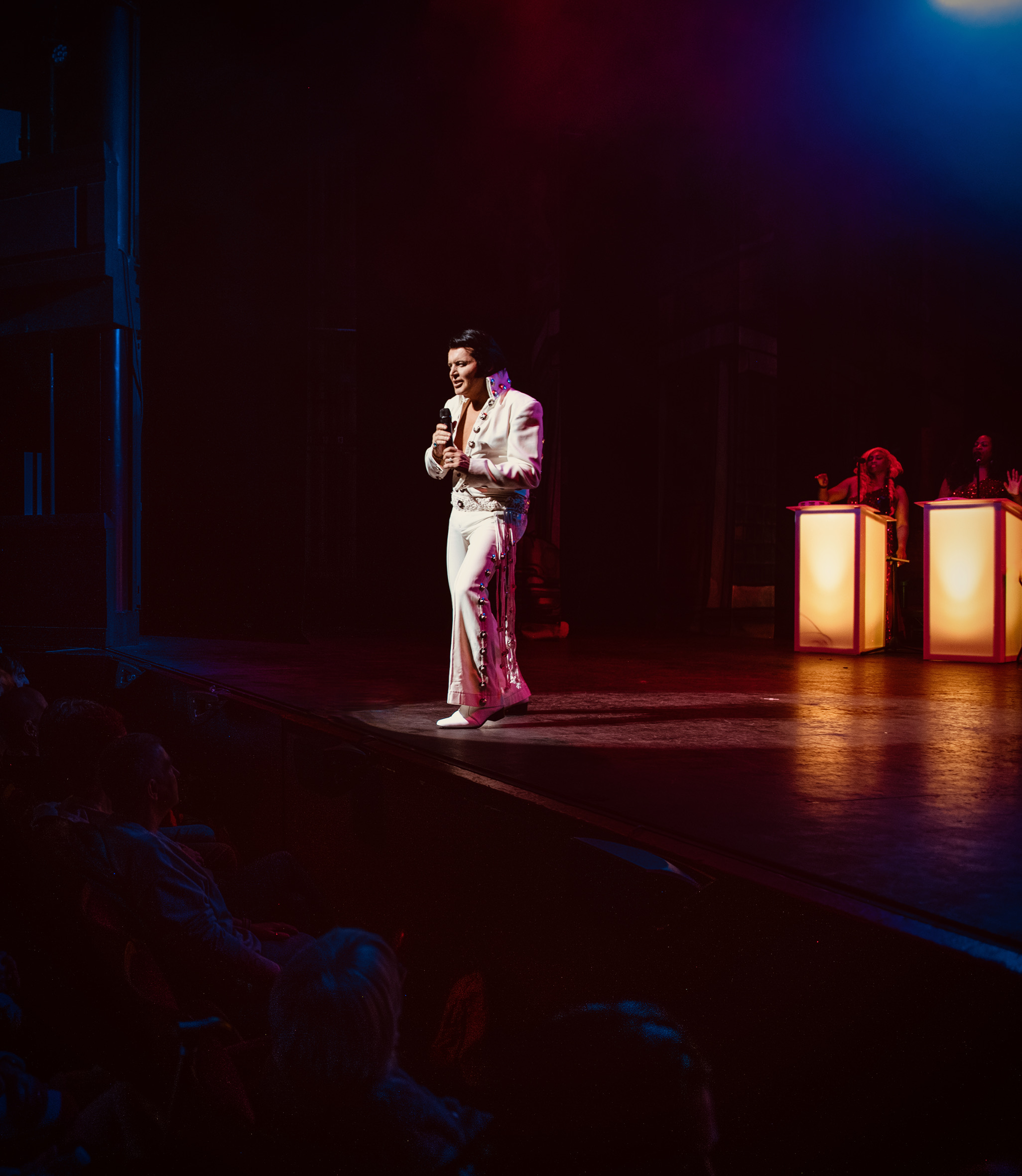 Rob Kingsley performing A Vision of Elvis live on stage in a white concho Elvis jumpsuit with backing vocalists