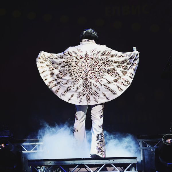 Rob Kingsley performing A Vision of Elvis live on stage with his Elvis cape spread under dramatic concert lighting 👑📸