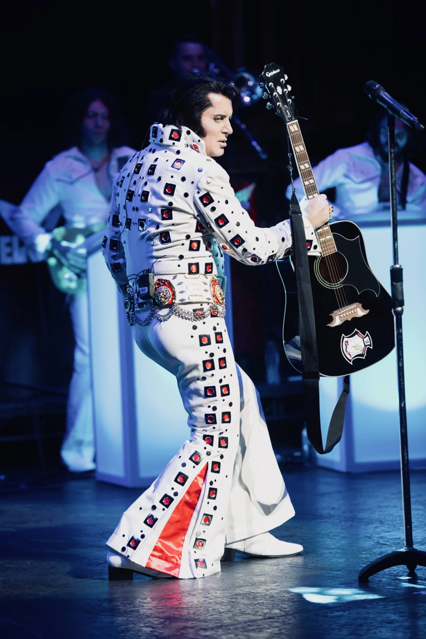 Rob Kingsley performing with guitar in his white Elvis jumpsuit